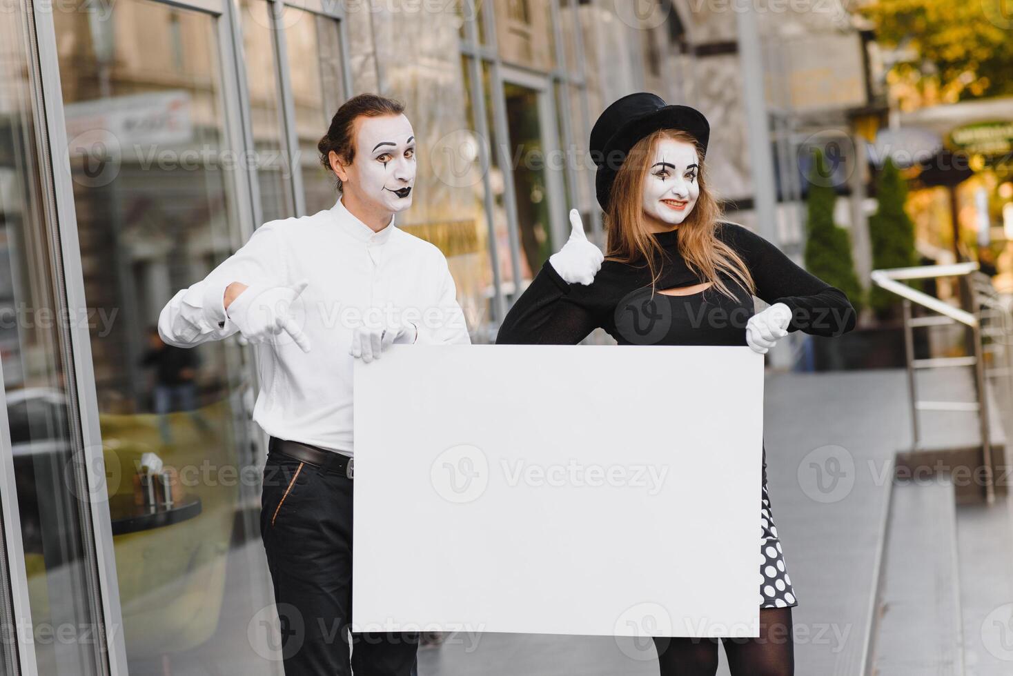 Your text here. Actors mimes holding empty white letter. Colorful portrait with gray background. April fools day photo