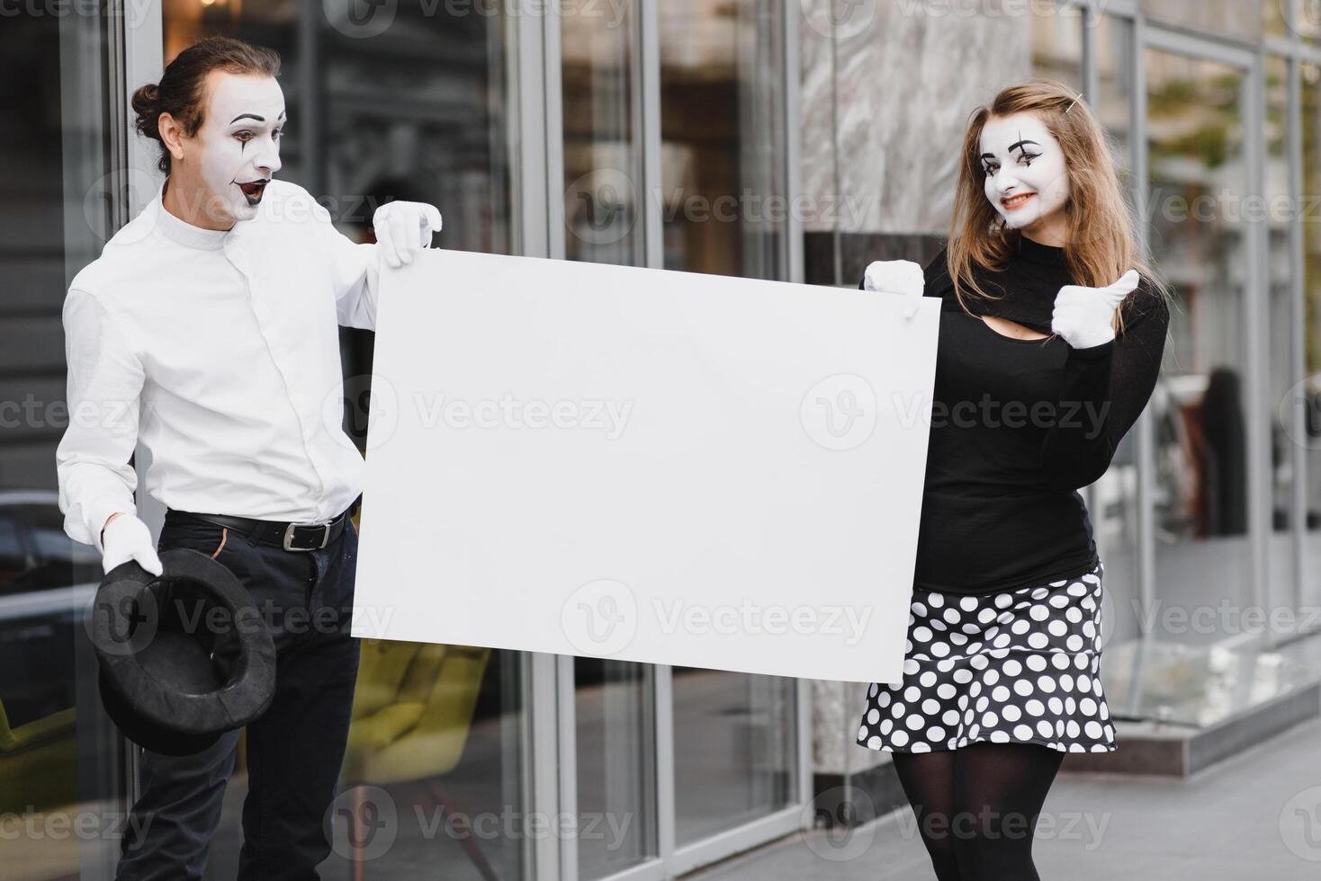 Your text here. Actors mimes holding empty white letter. Colorful portrait with gray background. April fools day photo