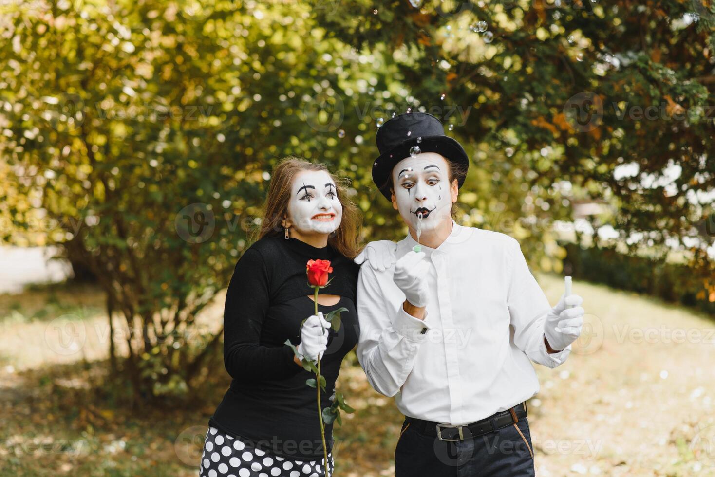 Mime artist blowing a bubble through wand on green background photo