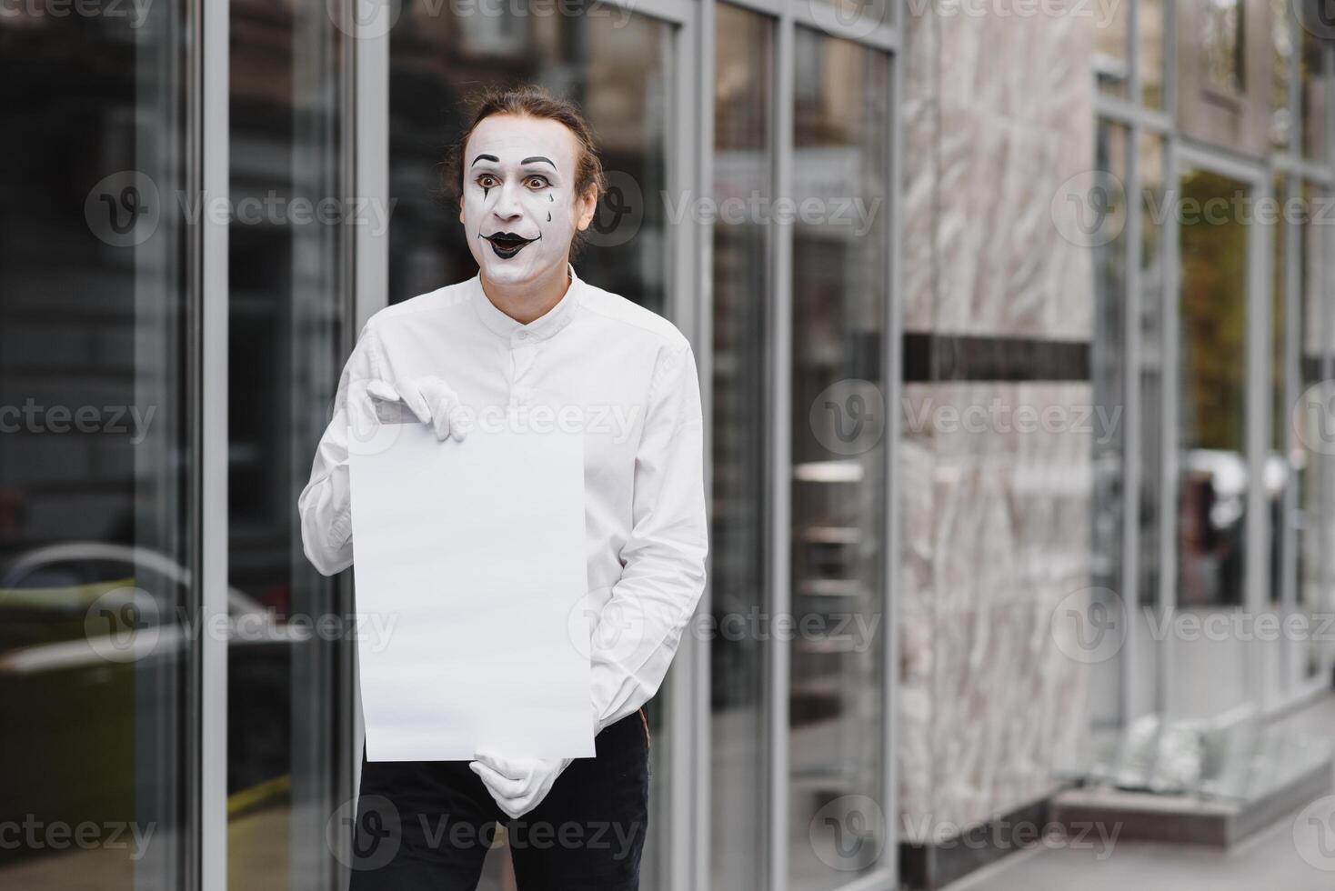 Your text here. Actor mime holding empty white letter. Colorful portrait with gray background. April fools day photo