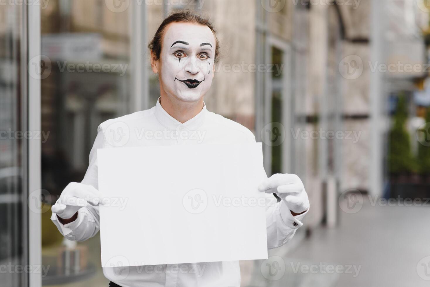 Your text here. Actor mime holding empty white letter. Colorful portrait with gray background. April fools day photo