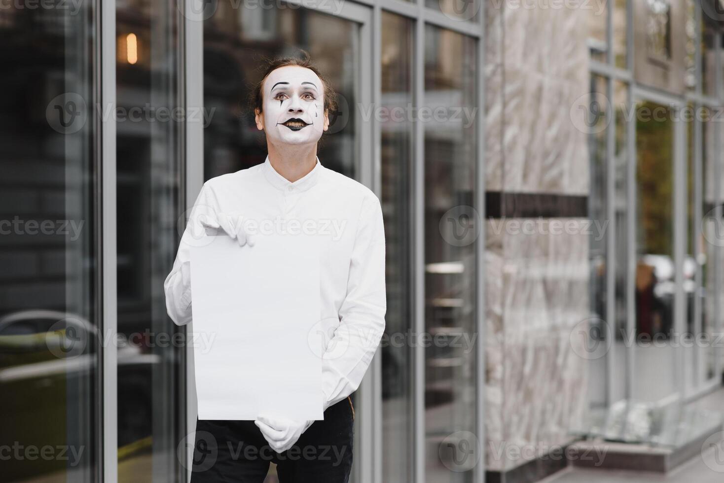 Your text here. Actor mime holding empty white letter. Colorful portrait with gray background. April fools day photo