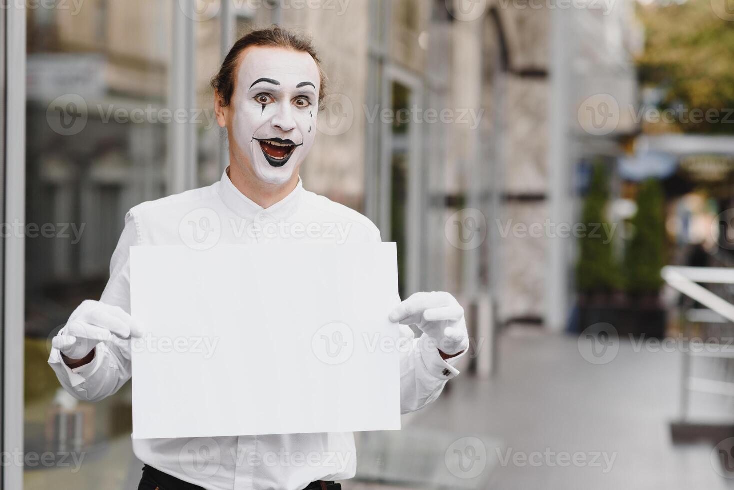 Your text here. Actor mime holding empty white letter. Colorful portrait with gray background. April fools day photo