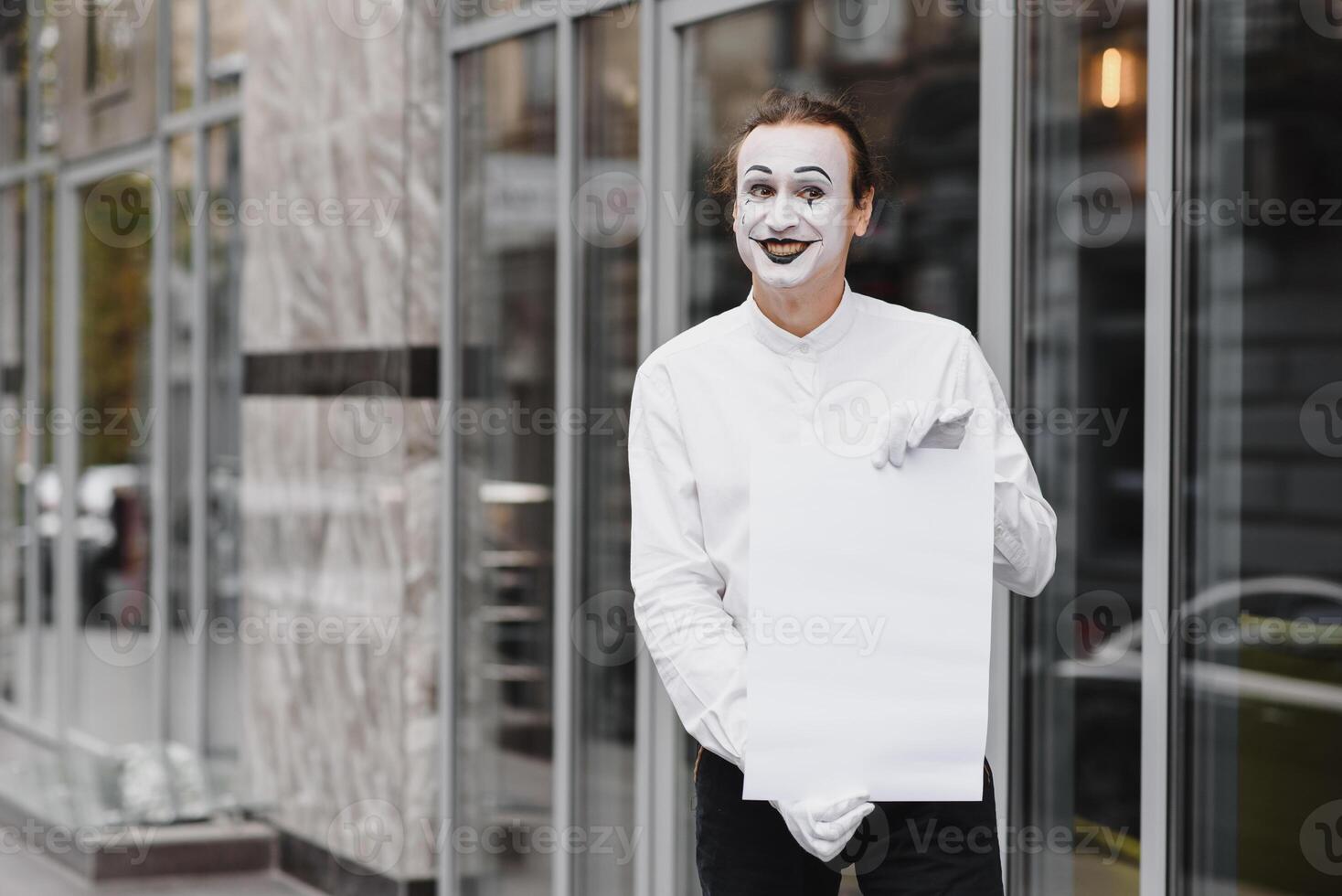 Your text here. Actor mime holding empty white letter. Colorful portrait with gray background. April fools day photo