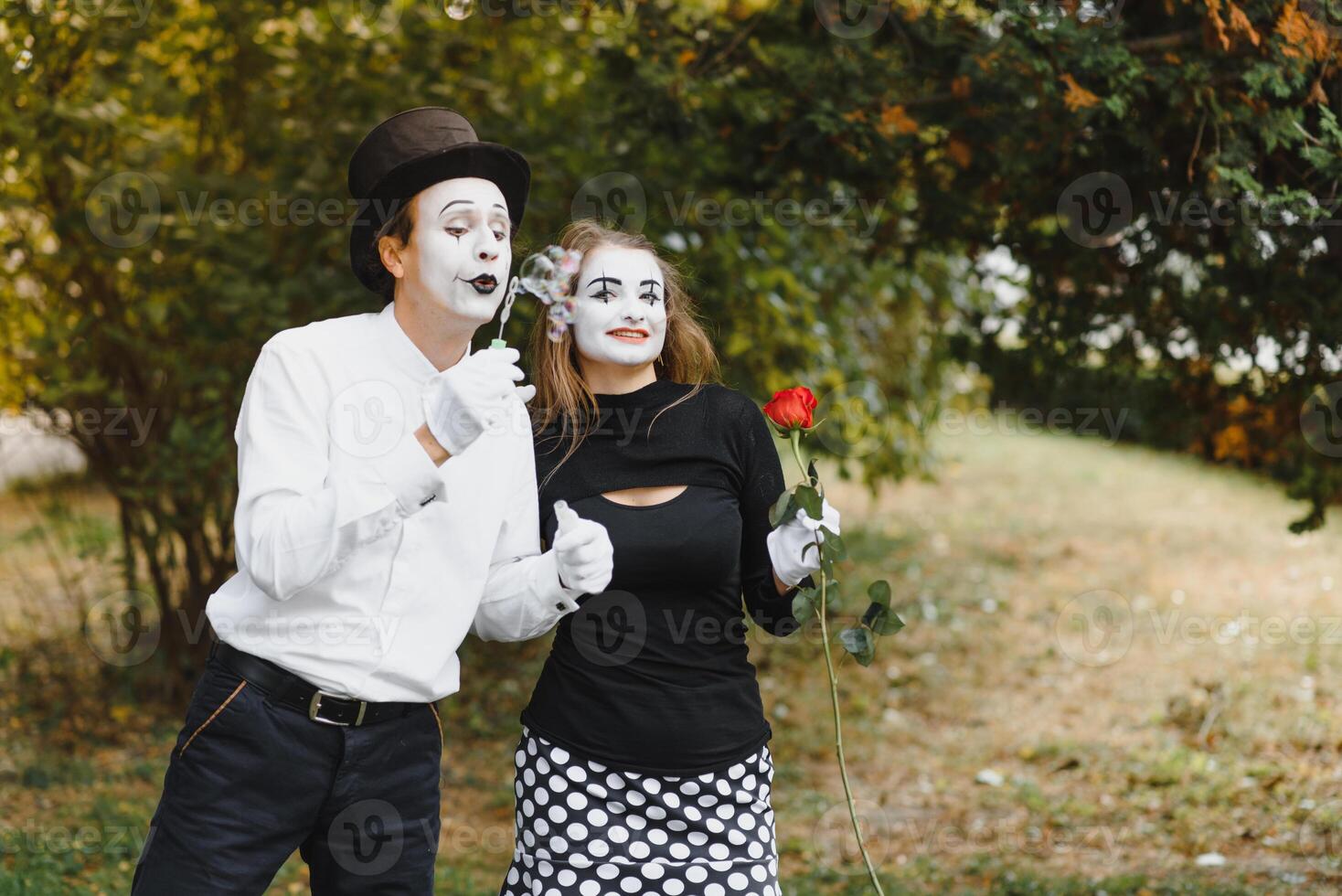 Mime artist blowing a bubble through wand on green background photo