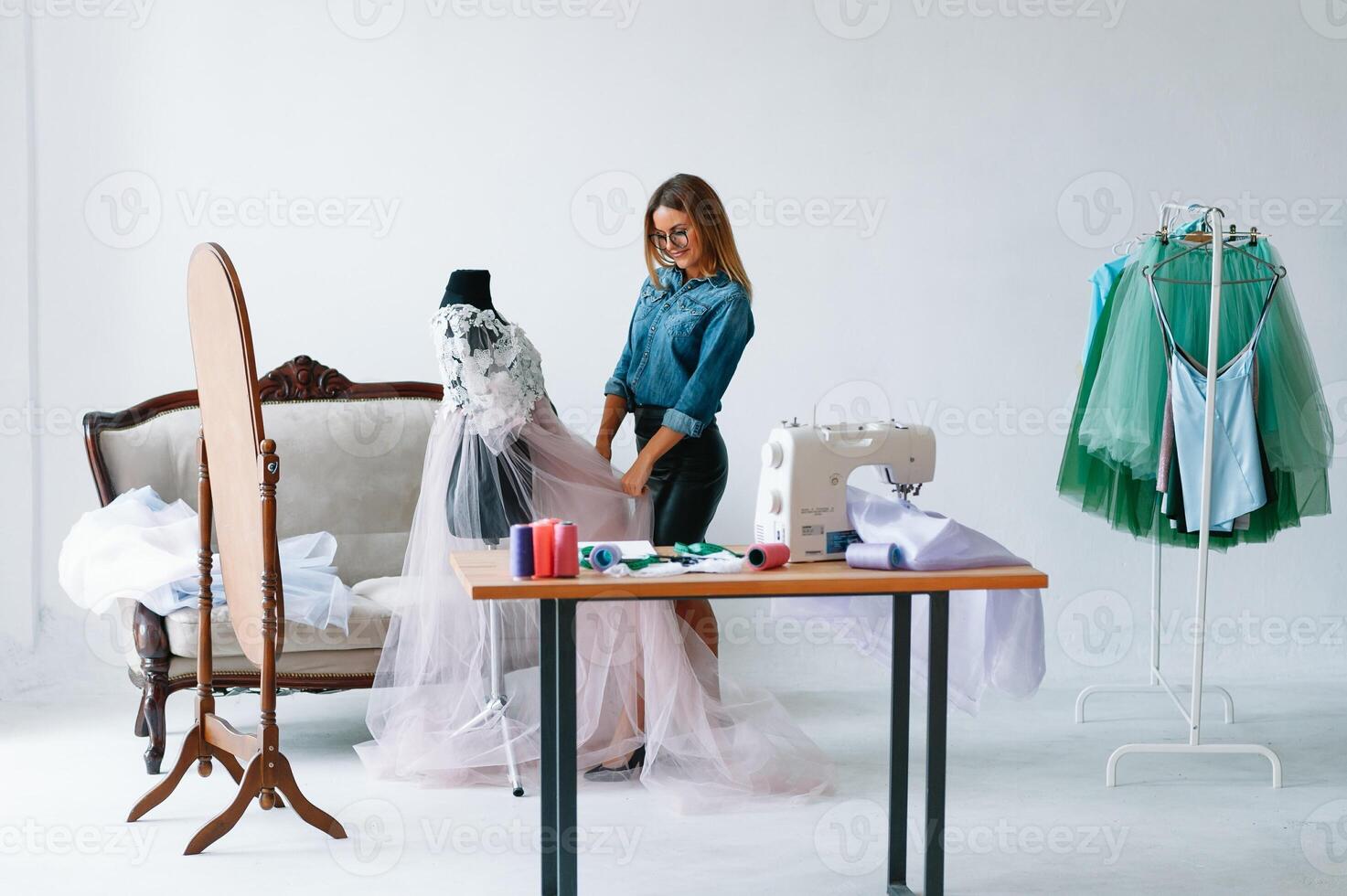 Attractive female fashion designer is working in her workshop. Stylish woman in process of creating new clothes collection photo