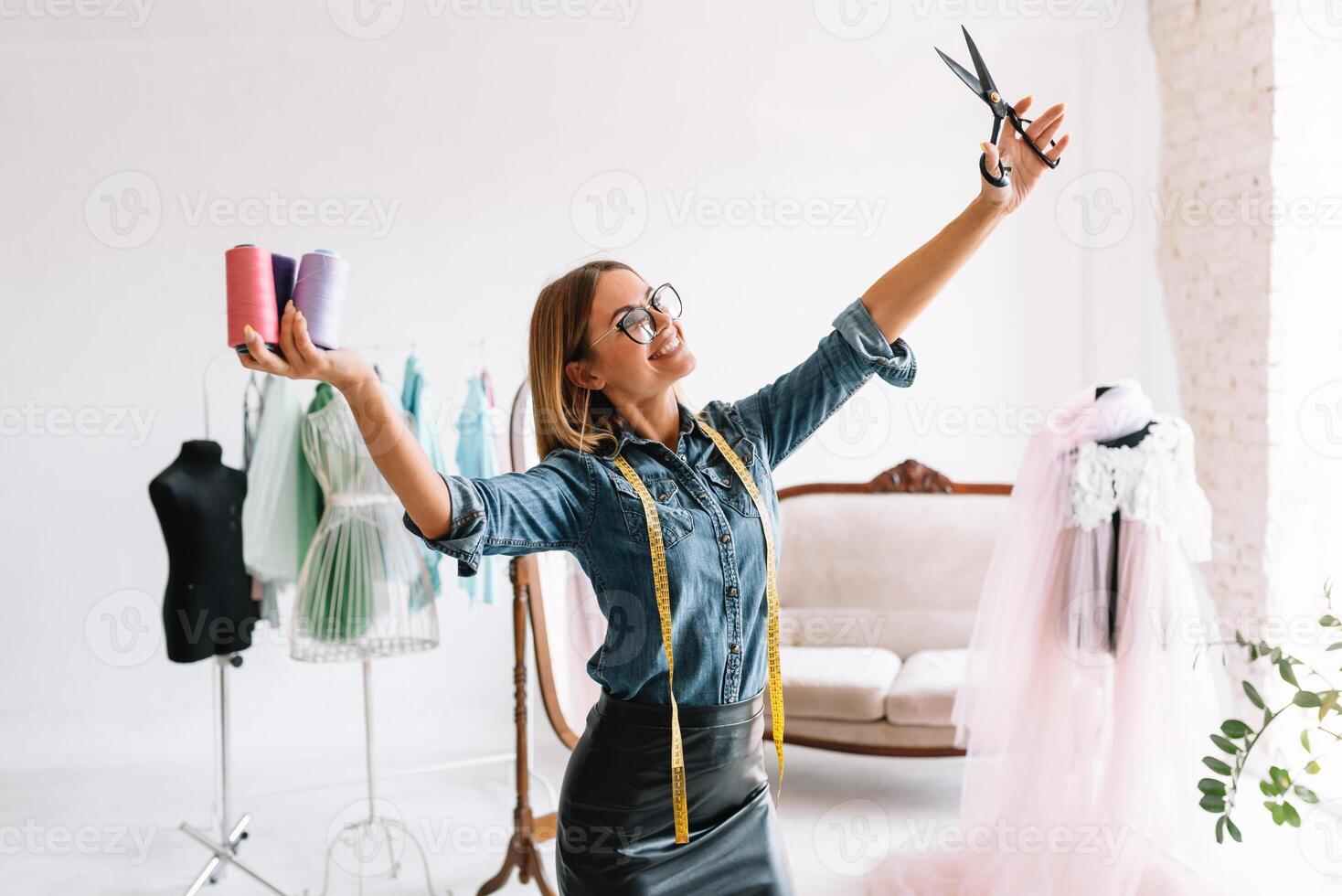 Portrait of female dress maker standing at her atelier and holding tailor tape. Successful adult business woman employed at her own business. photo