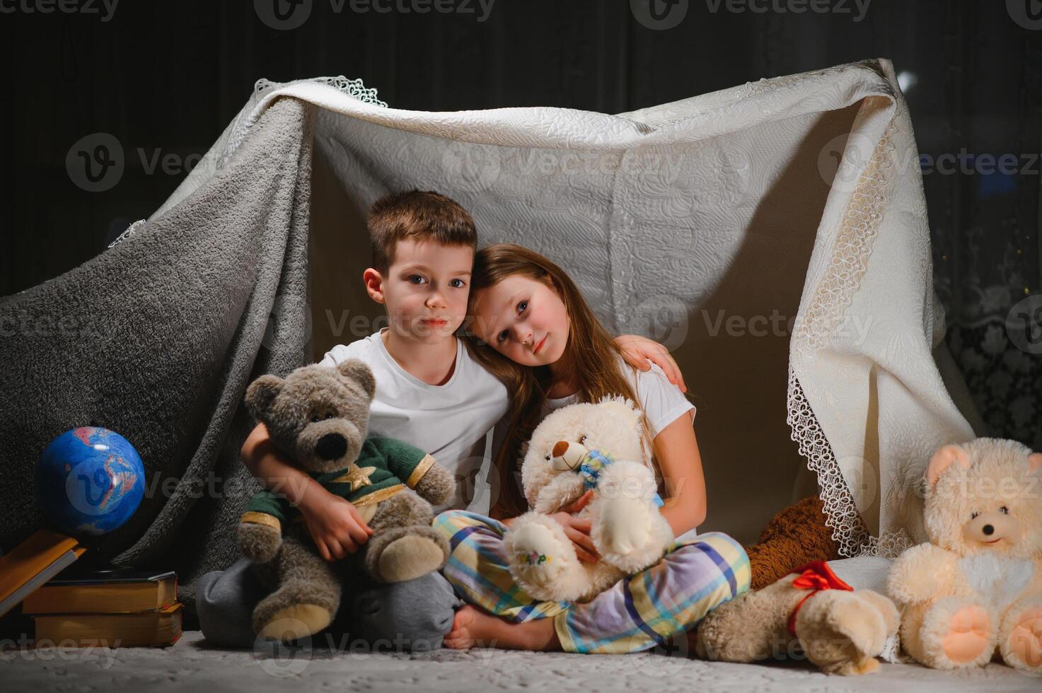 reading and family games in children's tent. boy and girl with book and flashlight before going to bed photo