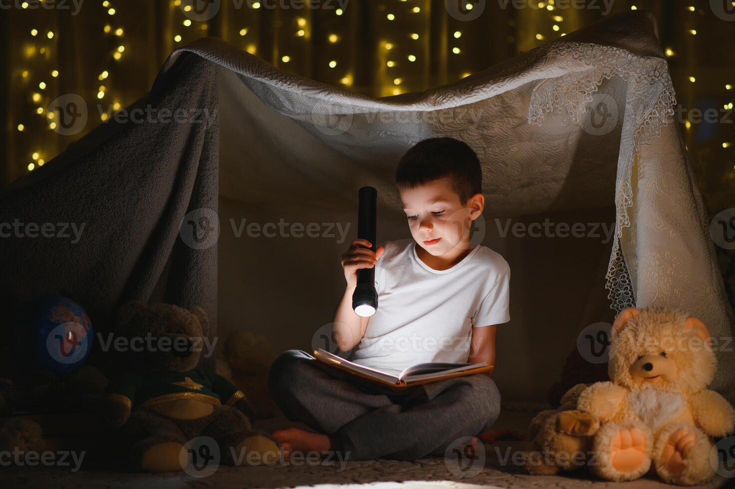 the child is reading a book with a flashlight photo