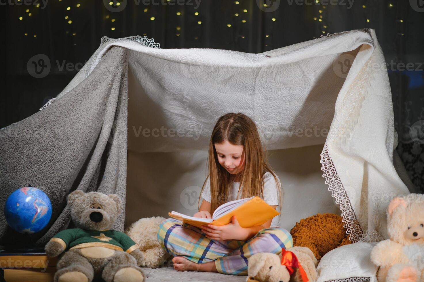 A pretty little girl reading a book on the floor under the lamp. Children and education. photo