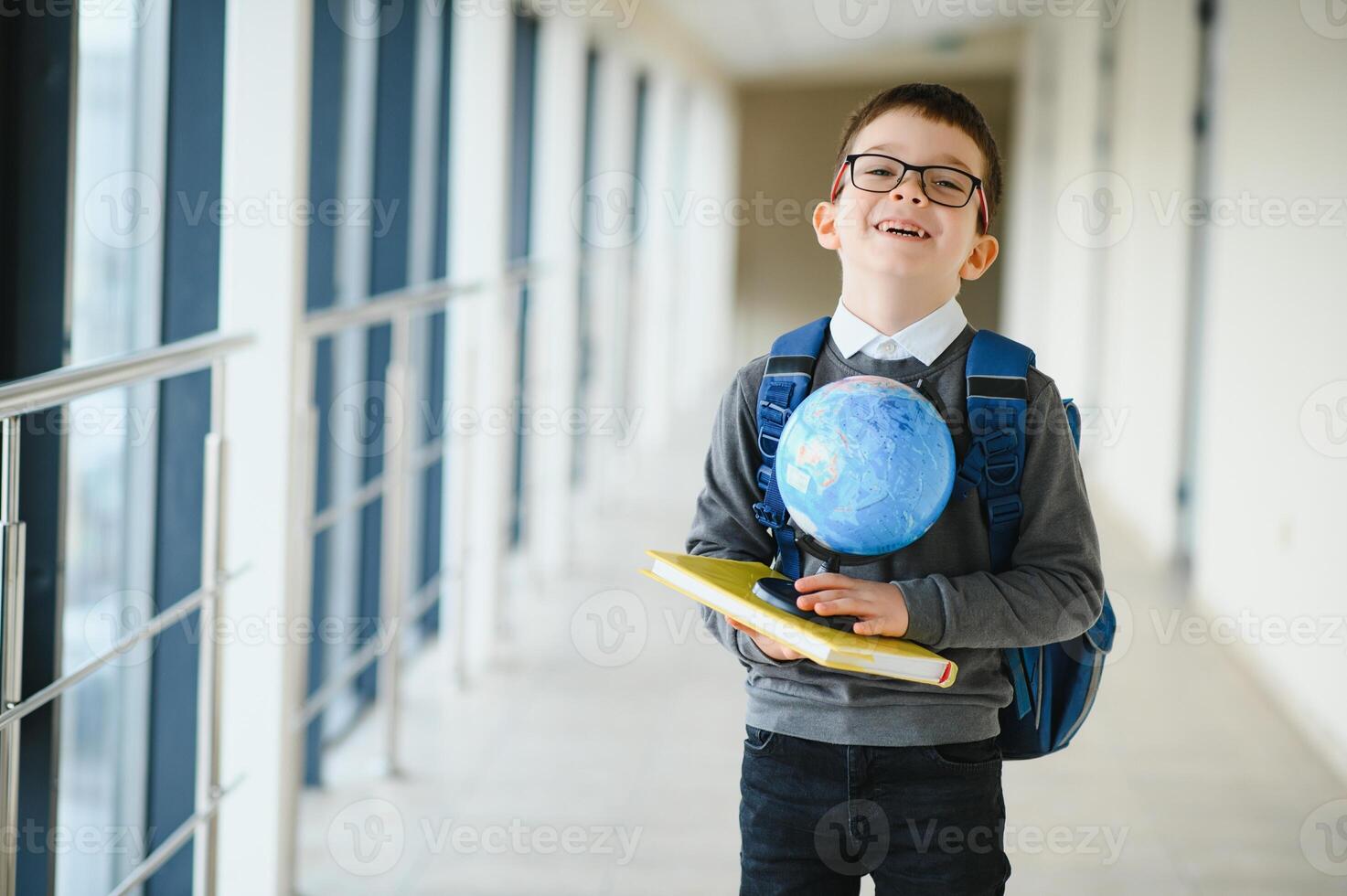 Schoolboy with schoolbag and books in the school. Education concept. Back to school. Schoolkid going to class. Stylish boy with backpack. Boy ready to study photo