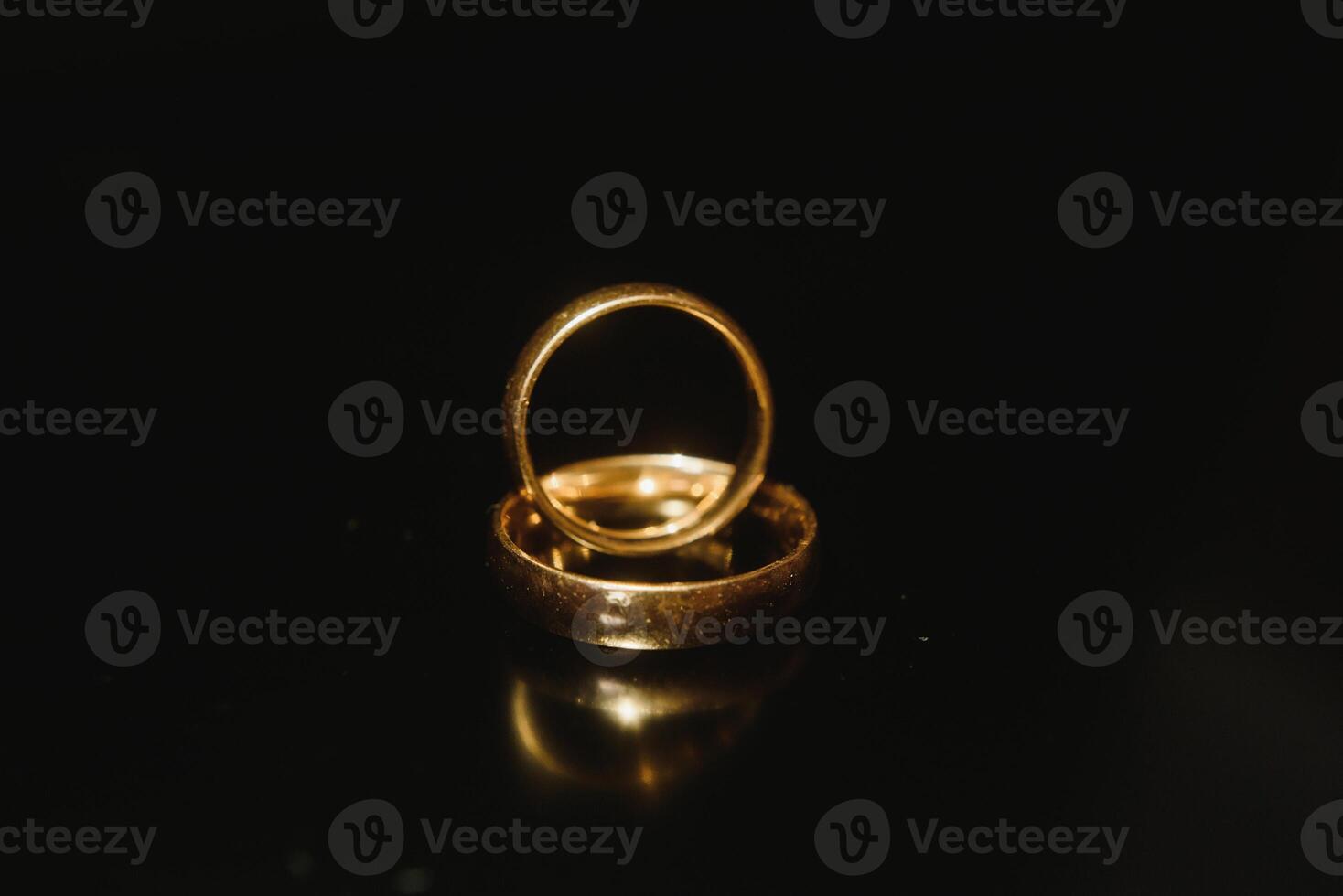 Elegant wedding rings for the bride and groom on a black background with highlights, macro, selective focus. photo