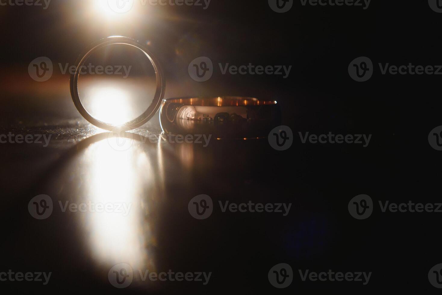 Elegant wedding rings for the bride and groom on a black background with highlights, macro, selective focus. photo