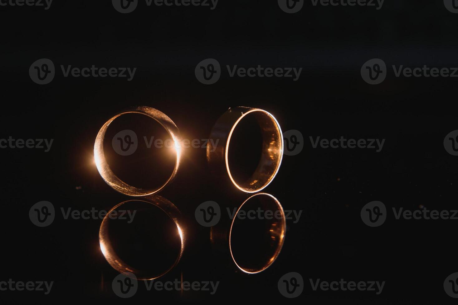 Elegant wedding rings for the bride and groom on a black background with highlights, macro, selective focus. photo