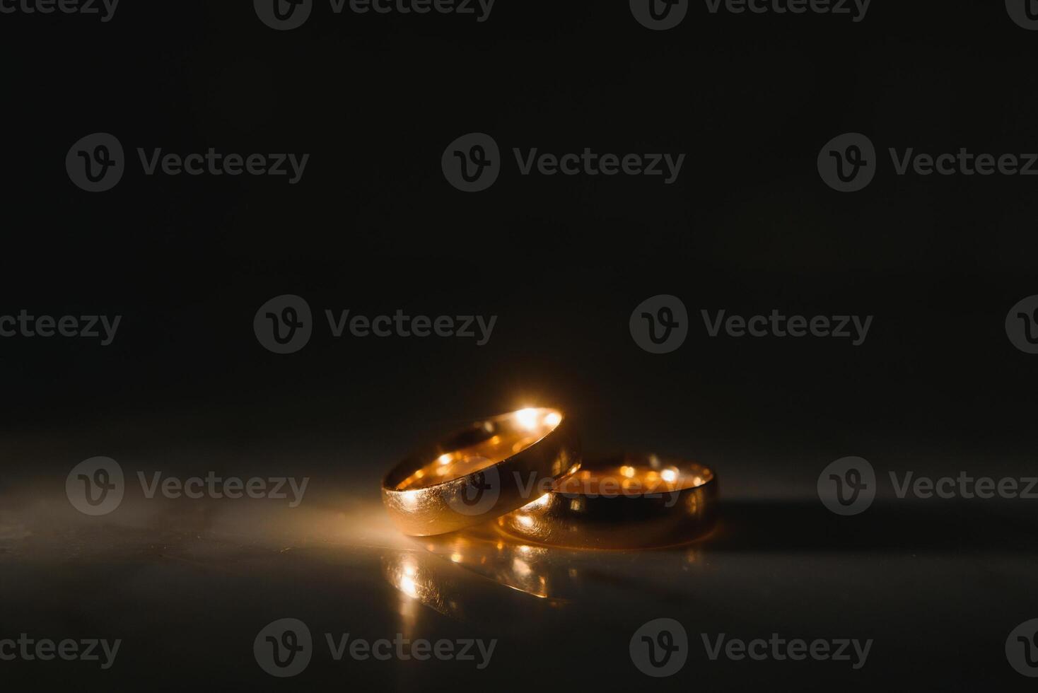 Elegant wedding rings for the bride and groom on a black background with highlights, macro, selective focus. photo