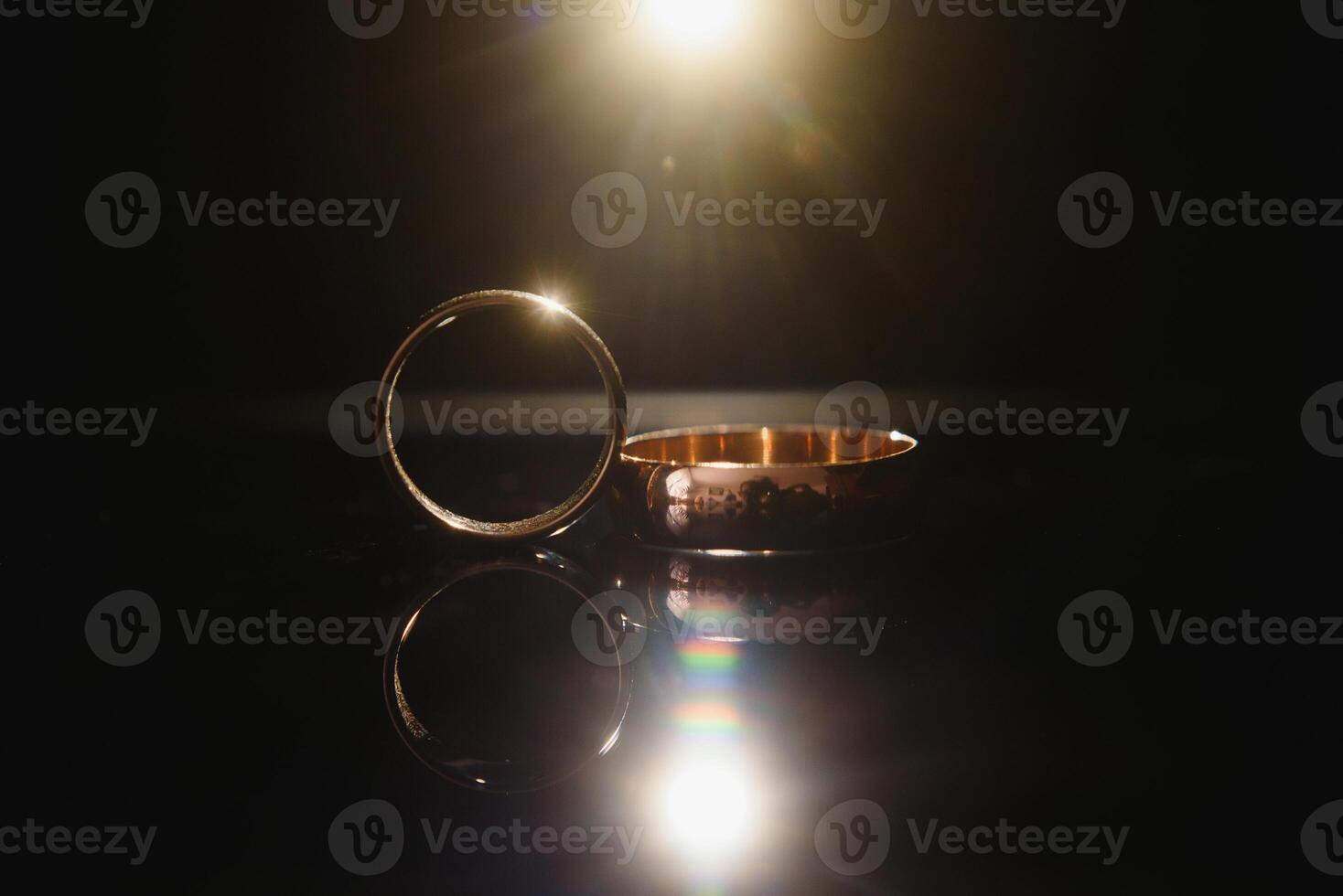 Elegant wedding rings for the bride and groom on a black background with highlights, macro, selective focus. photo