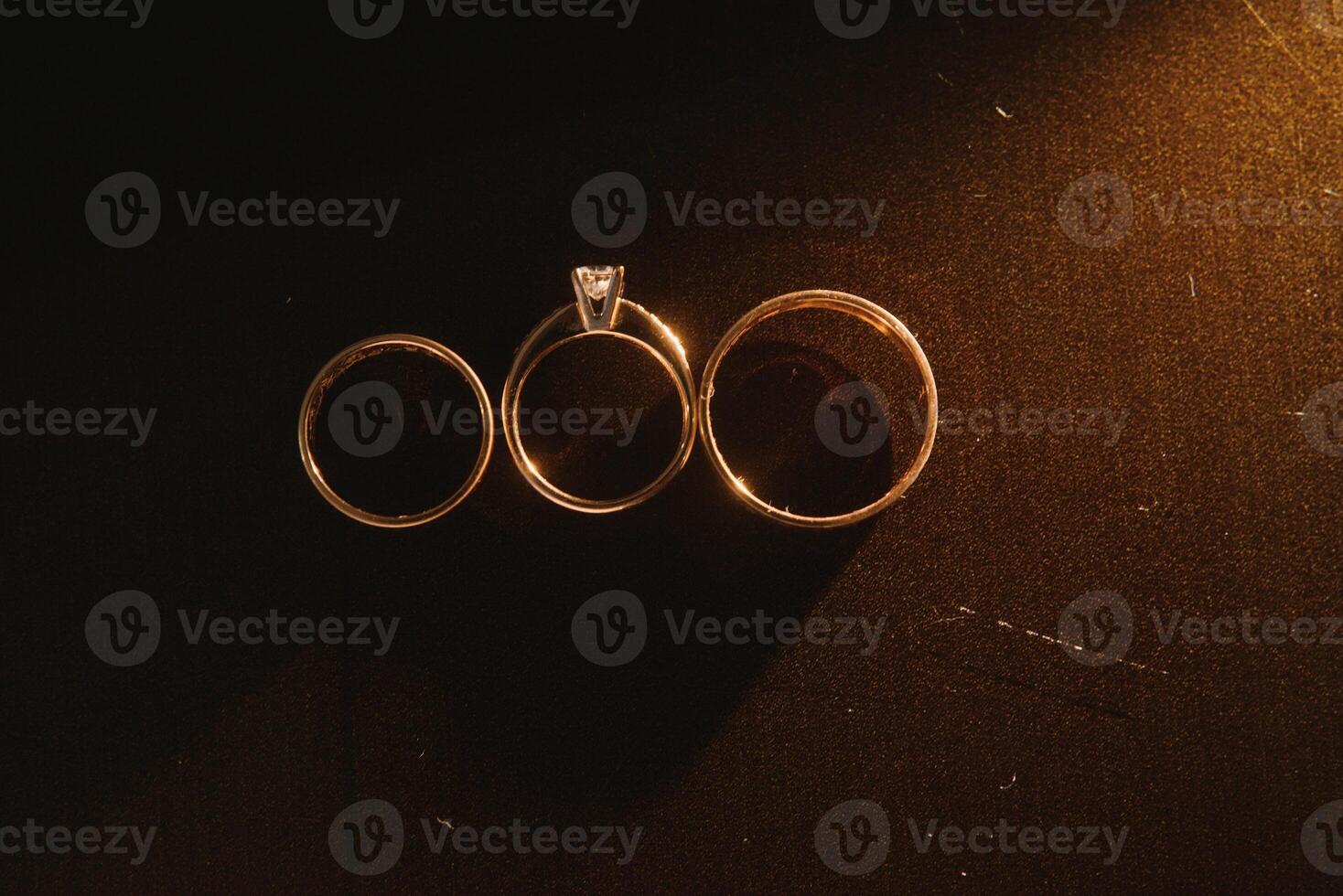 Elegant wedding rings for the bride and groom on a black background with highlights, macro, selective focus. photo