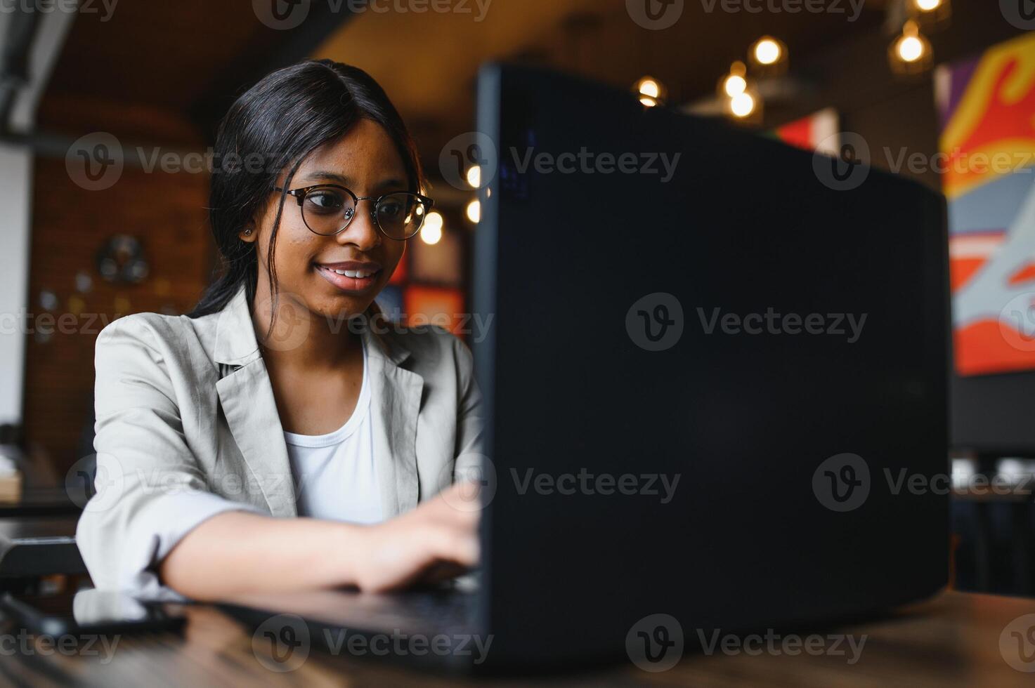 Happy african american woman worker using laptop work study at computer in loft office or cafe, smiling mixed race female student freelancer using pc app dating communicating online watching webinar photo
