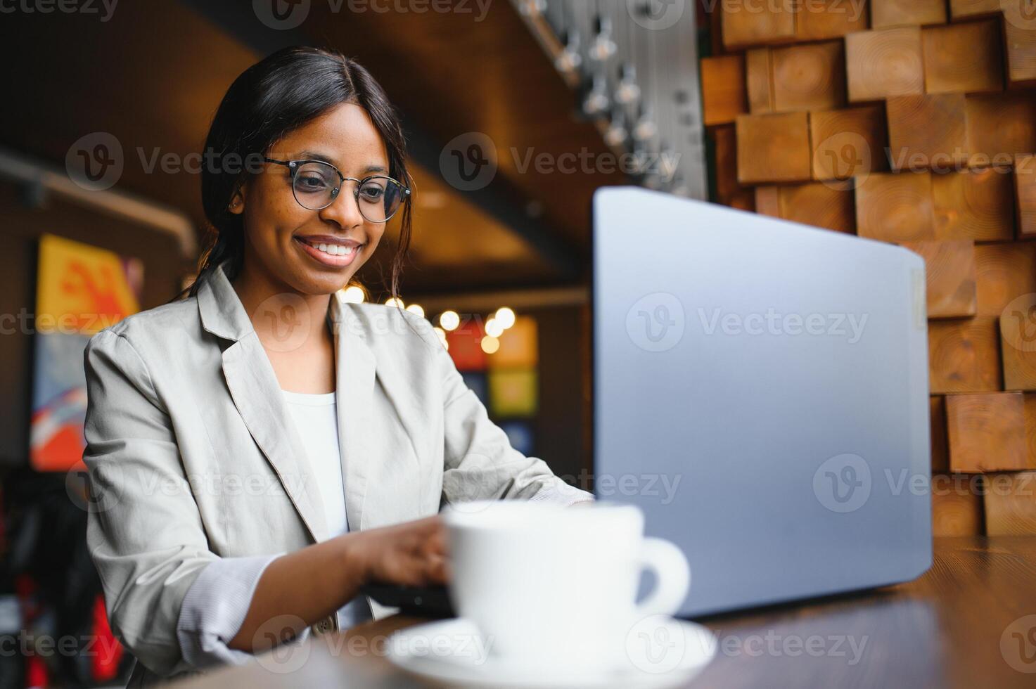 Happy african american woman worker using laptop work study at computer in loft office or cafe, smiling mixed race female student freelancer using pc app dating communicating online watching webinar photo