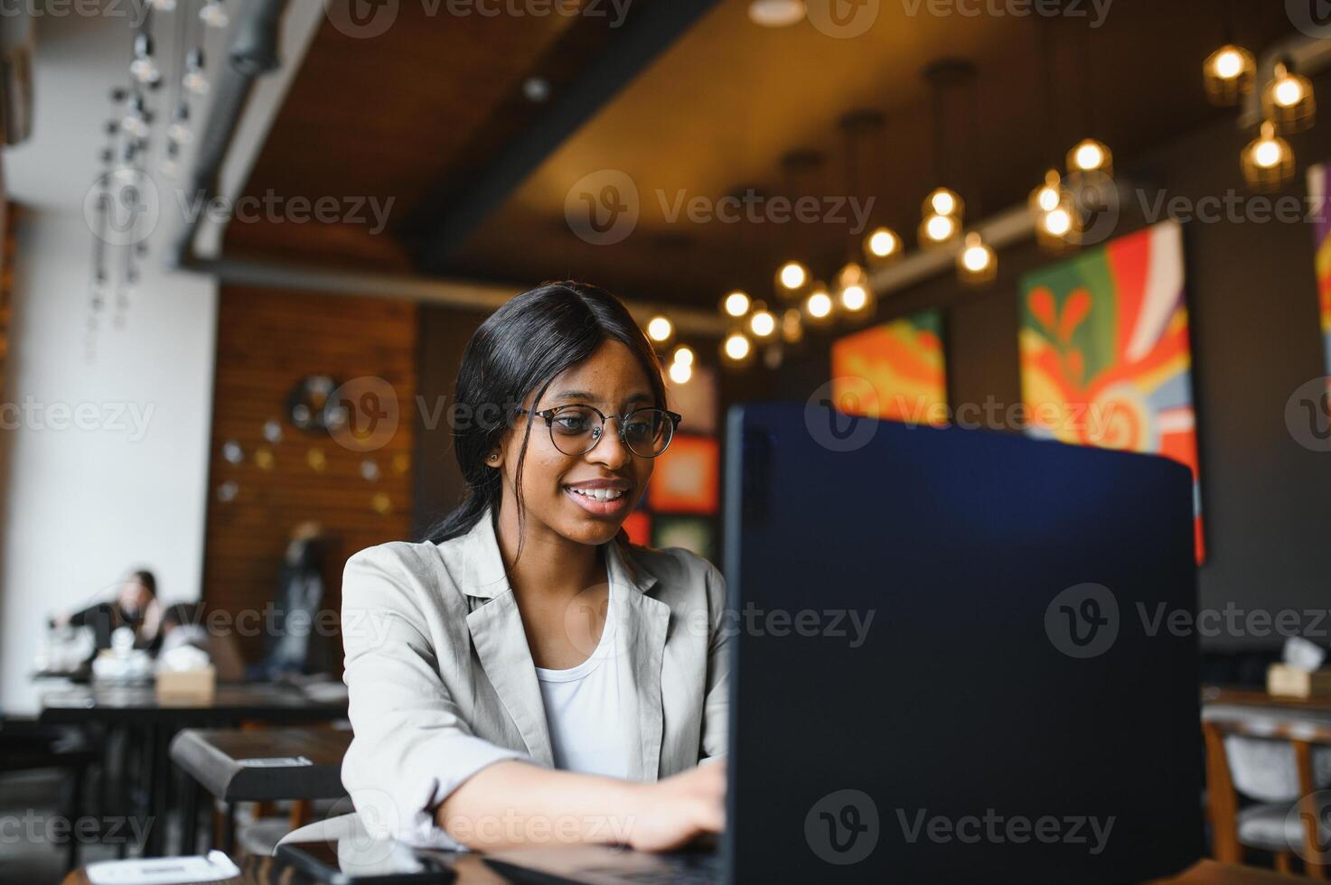 Happy african american woman worker using laptop work study at computer in loft office or cafe, smiling mixed race female student freelancer using pc app dating communicating online watching webinar photo