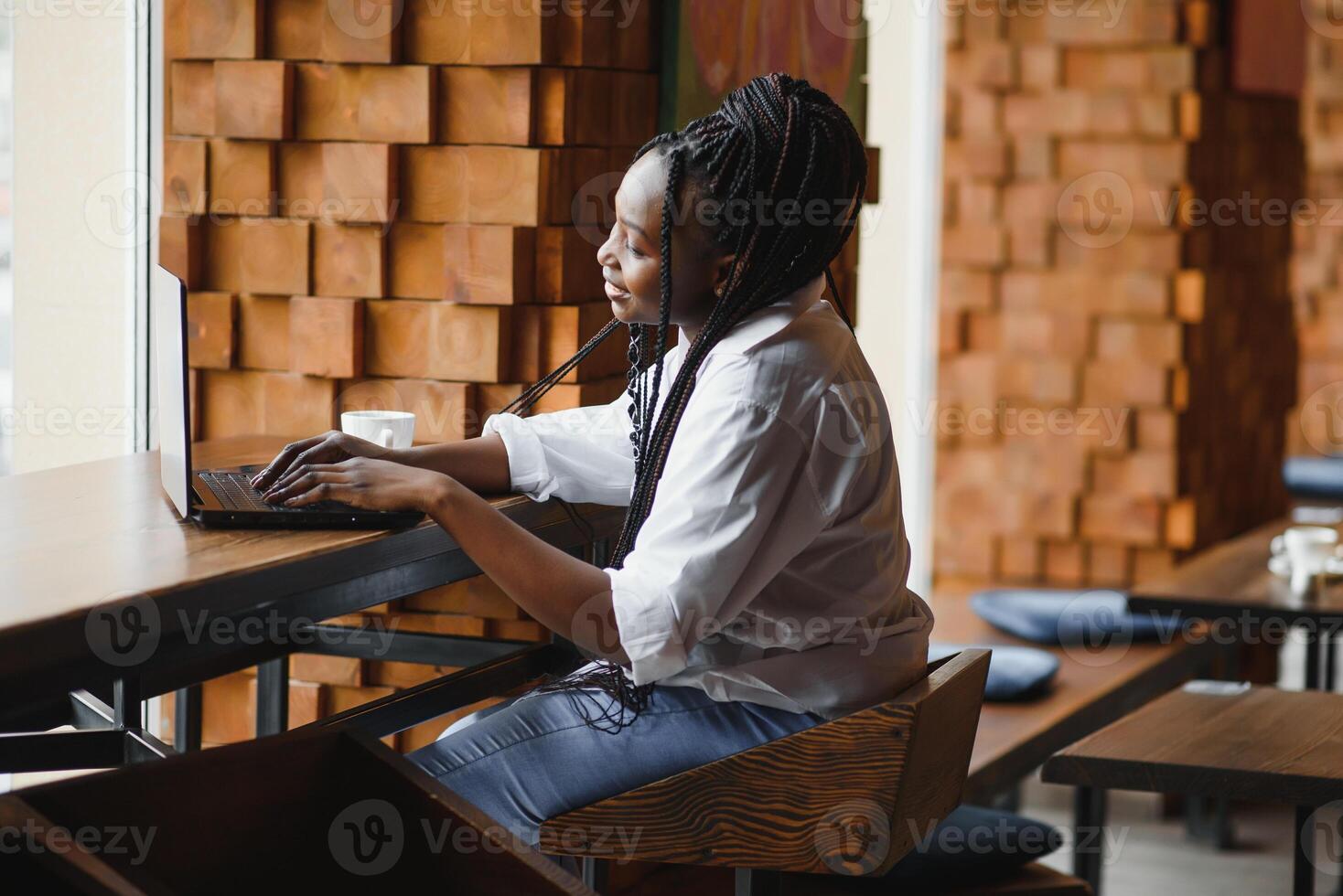 Happy african american woman worker using laptop work study at computer in loft office or cafe, smiling mixed race female student freelancer using pc app dating communicating online watching webinar photo