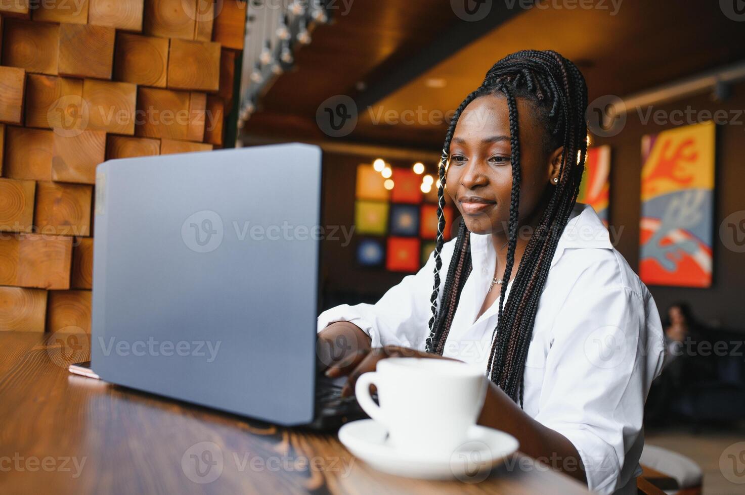 Happy african american woman worker using laptop work study at computer in loft office or cafe, smiling mixed race female student freelancer using pc app dating communicating online watching webinar photo