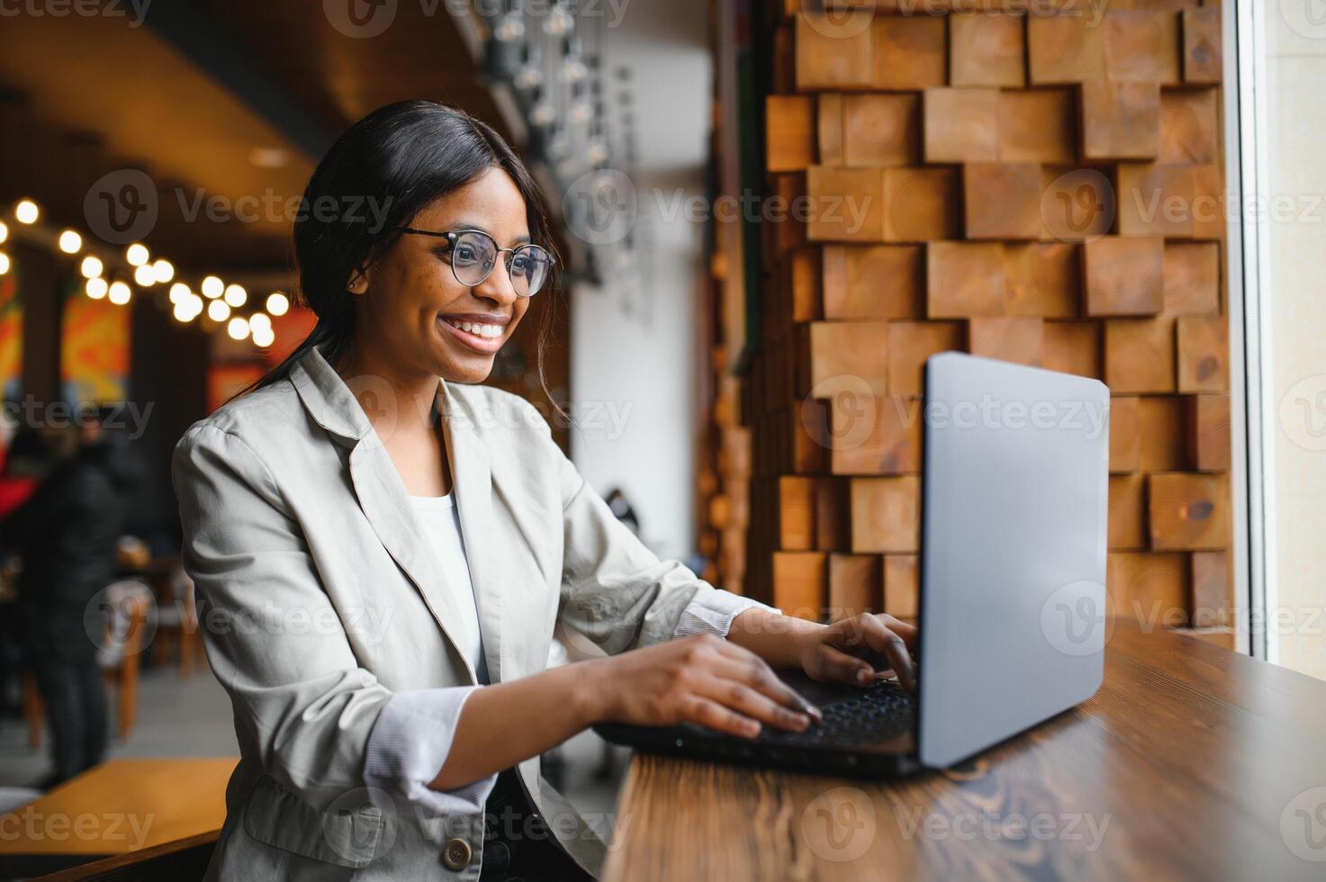 Happy african american woman worker using laptop work study at computer in loft office or cafe, smiling mixed race female student freelancer using pc app dating communicating online watching webinar photo
