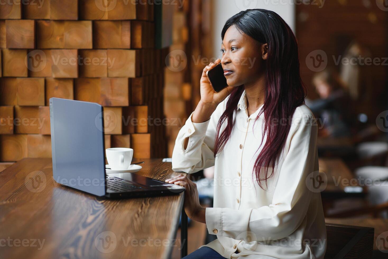 Young business woman is arranging the next business meeting in a modern coworking space by using a laptop. Young freelancer female is reading emails and other messages on a mobile phone. photo