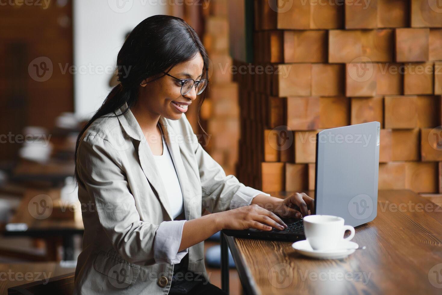 Happy african american woman worker using laptop work study at computer in loft office or cafe, smiling mixed race female student freelancer using pc app dating communicating online watching webinar photo