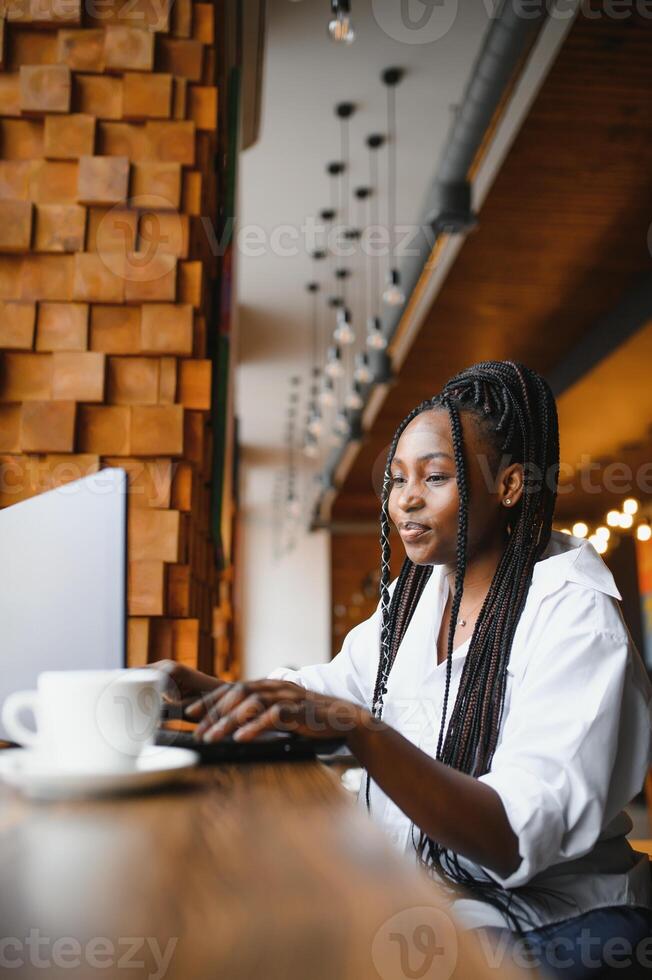 Happy african american woman worker using laptop work study at computer in loft office or cafe, smiling mixed race female student freelancer using pc app dating communicating online watching webinar photo
