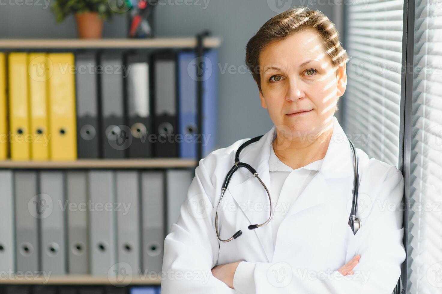 Portrait of middle age female doctor is wearing a white doctor's coat with a stethoscope around her neck. photo