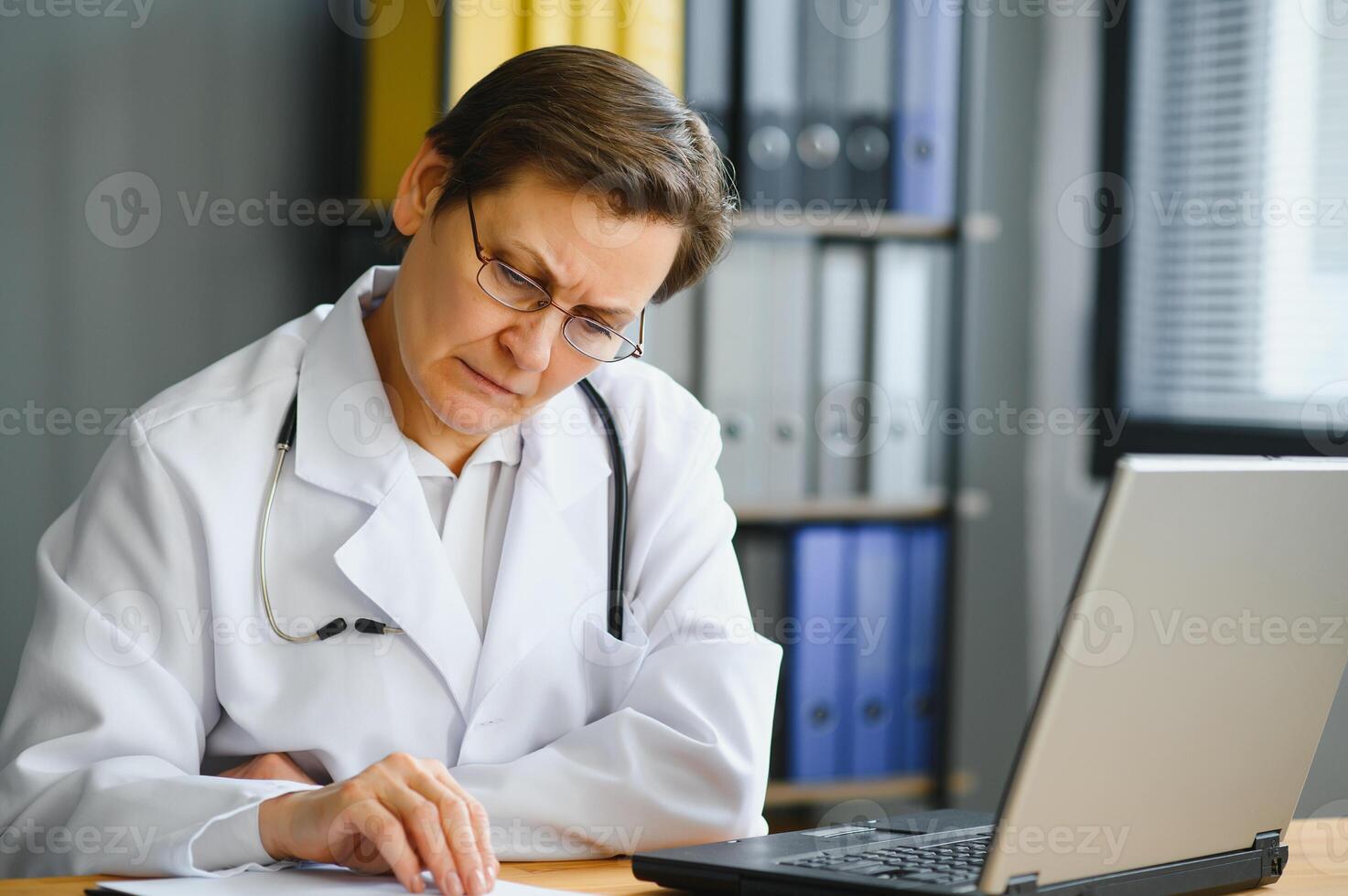 Portrait of mature female doctor in white coat at workplace photo