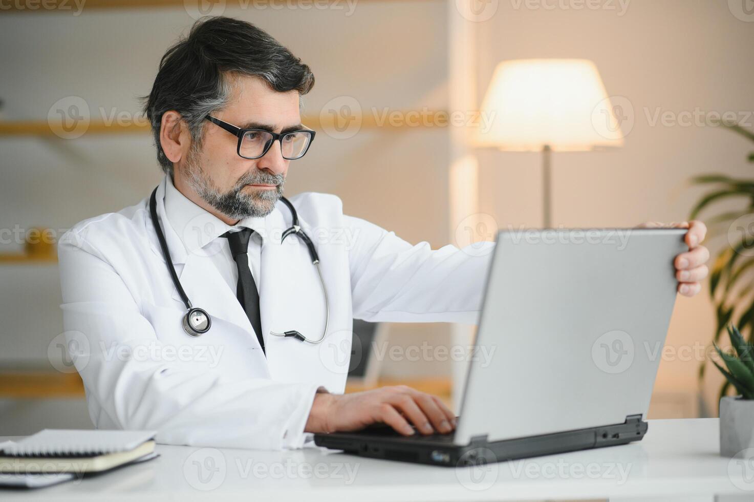 Portrait of a serious doctor using laptop in medical office photo