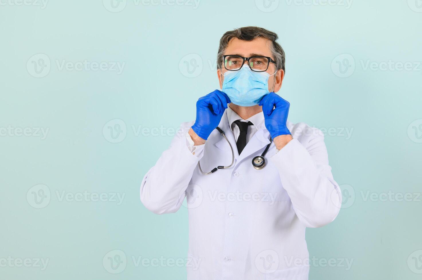 Portrait of a male doctor in a mask and gloves on a blue background. Healthcare concept photo