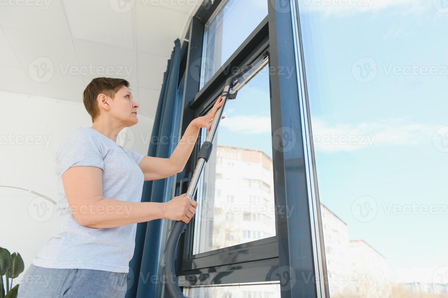An attractive middle-aged woman is washing a window in a room photo