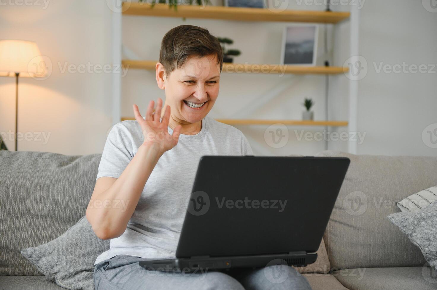 Elderly female sit on couch holding on lap laptop search information, check or typing e-mail, spend time on-line, modern tech, easy interesting pastimes services for retired older generation concept. photo
