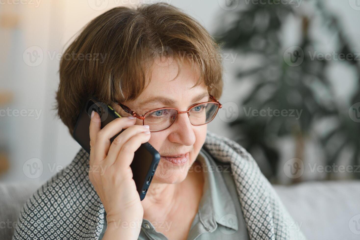 Handsome grandmother talking on the phone at home. photo