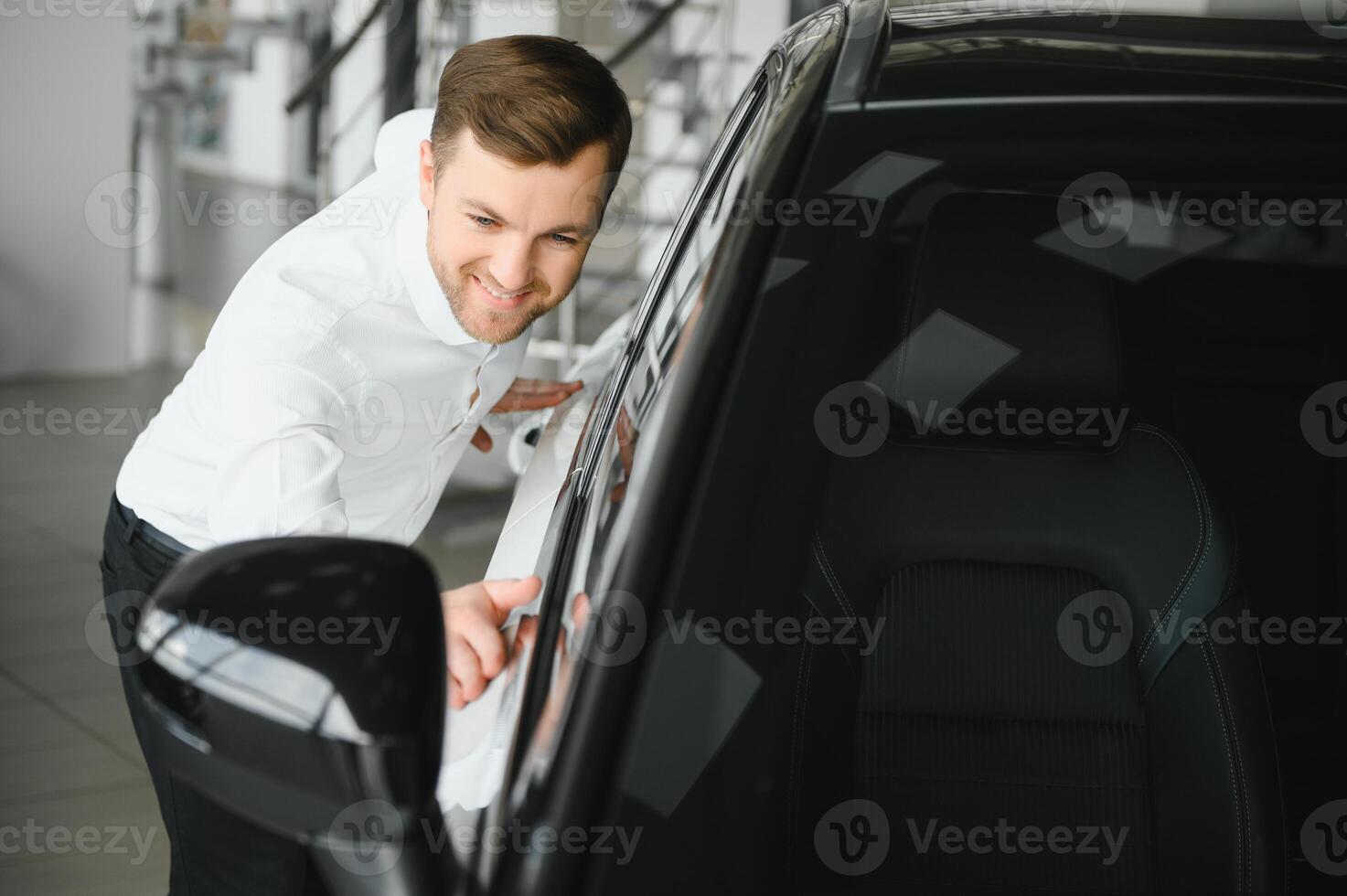 Man adult customer male buyer client chooses auto wants to buy new automobile touch check car in showroom vehicle salon dealership store motor show indoor. Sales concept photo