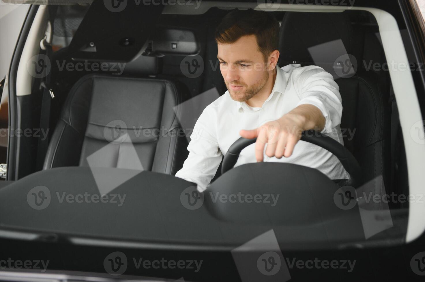 Taxi driver smiling while turning over to the backseat looking talking with clients. Successful businessman husband looking at the backseat at dealer shop before buying a car photo