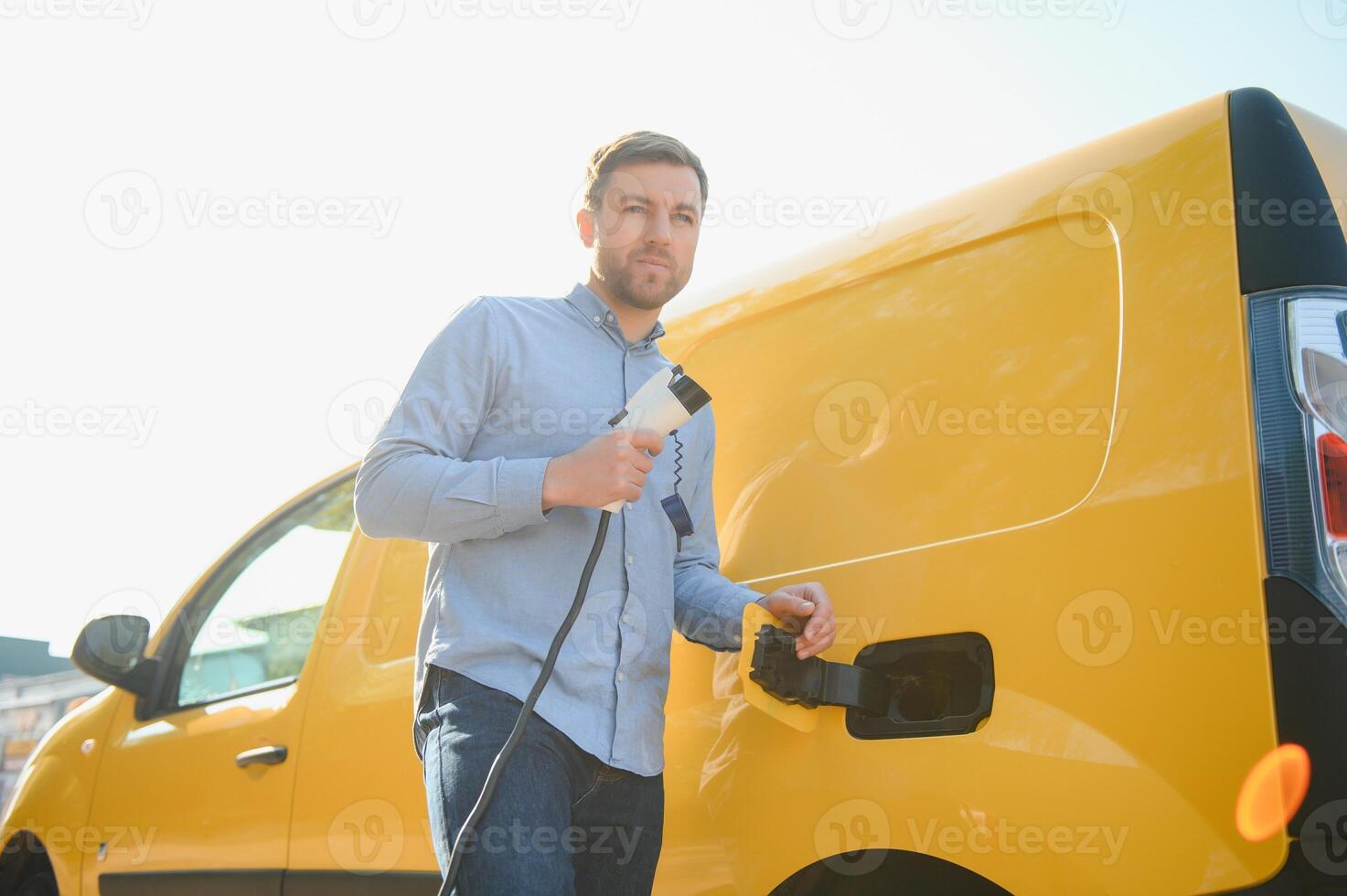 Smiling man unplugging the charger from the car photo