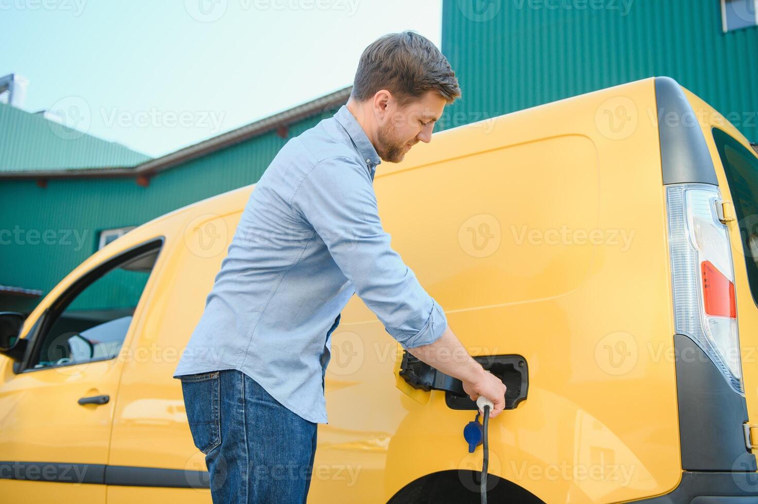 Smiling man unplugging the charger from the car photo