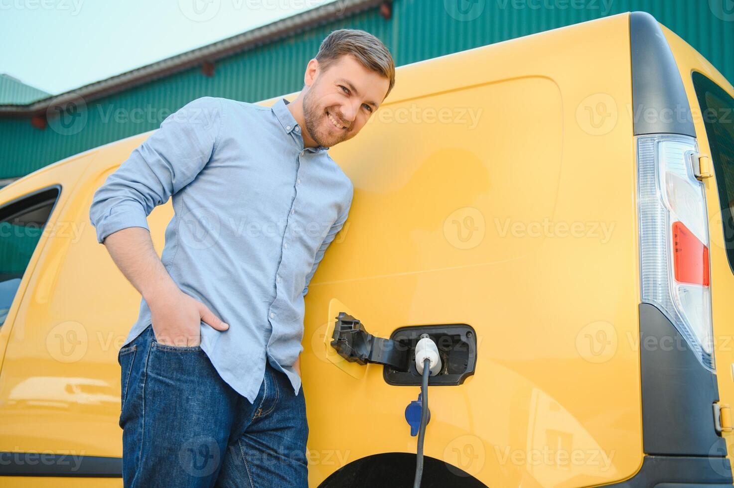 Smiling man unplugging the charger from the car photo