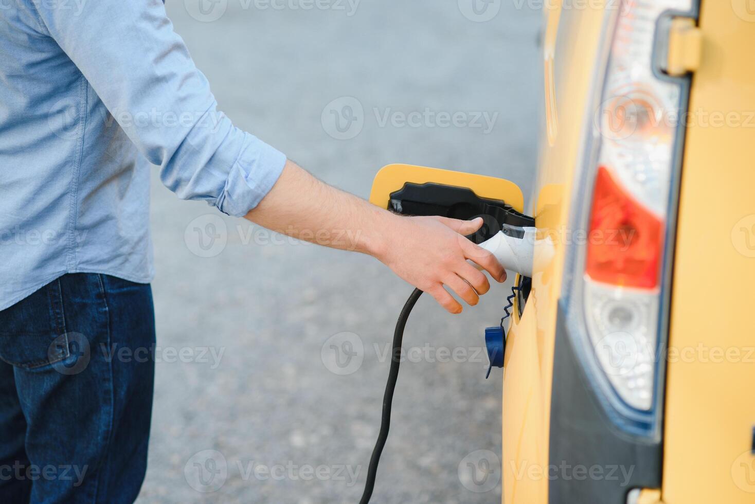 Smiling man unplugging the charger from the car photo