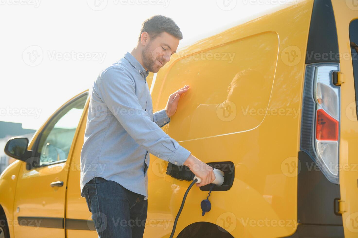 Smiling man unplugging the charger from the car photo