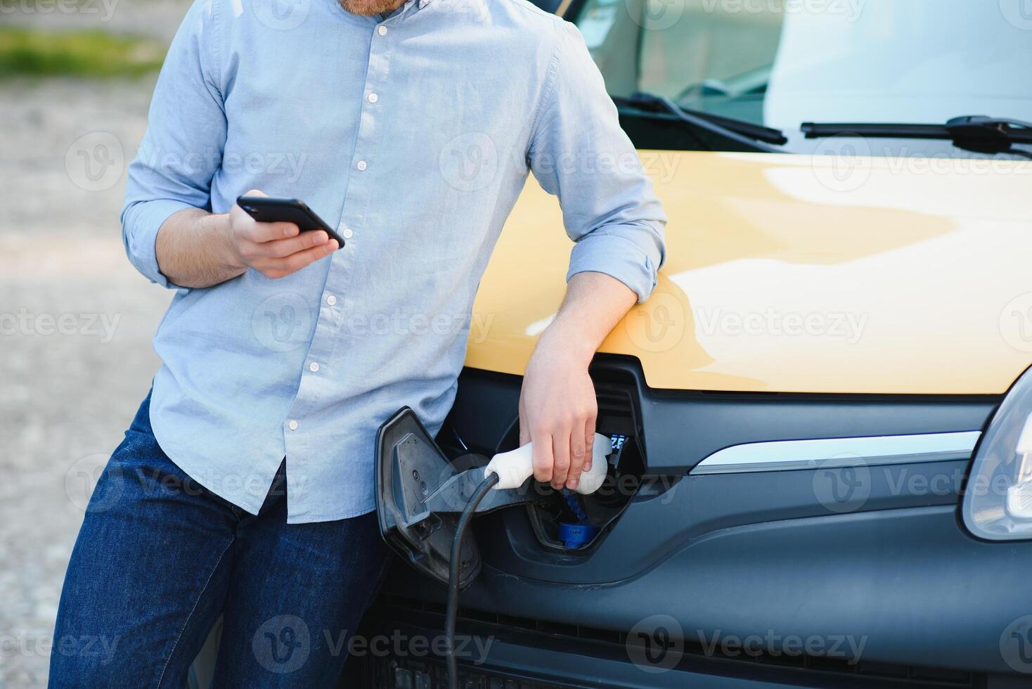 Smiling man unplugging the charger from the car photo