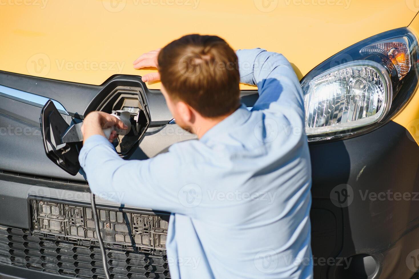 Smiling man unplugging the charger from the car photo