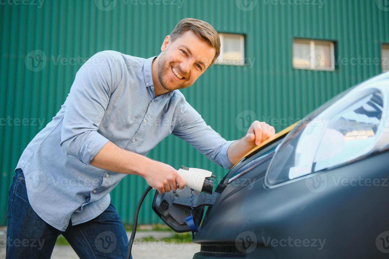 Smiling man unplugging the charger from the car photo