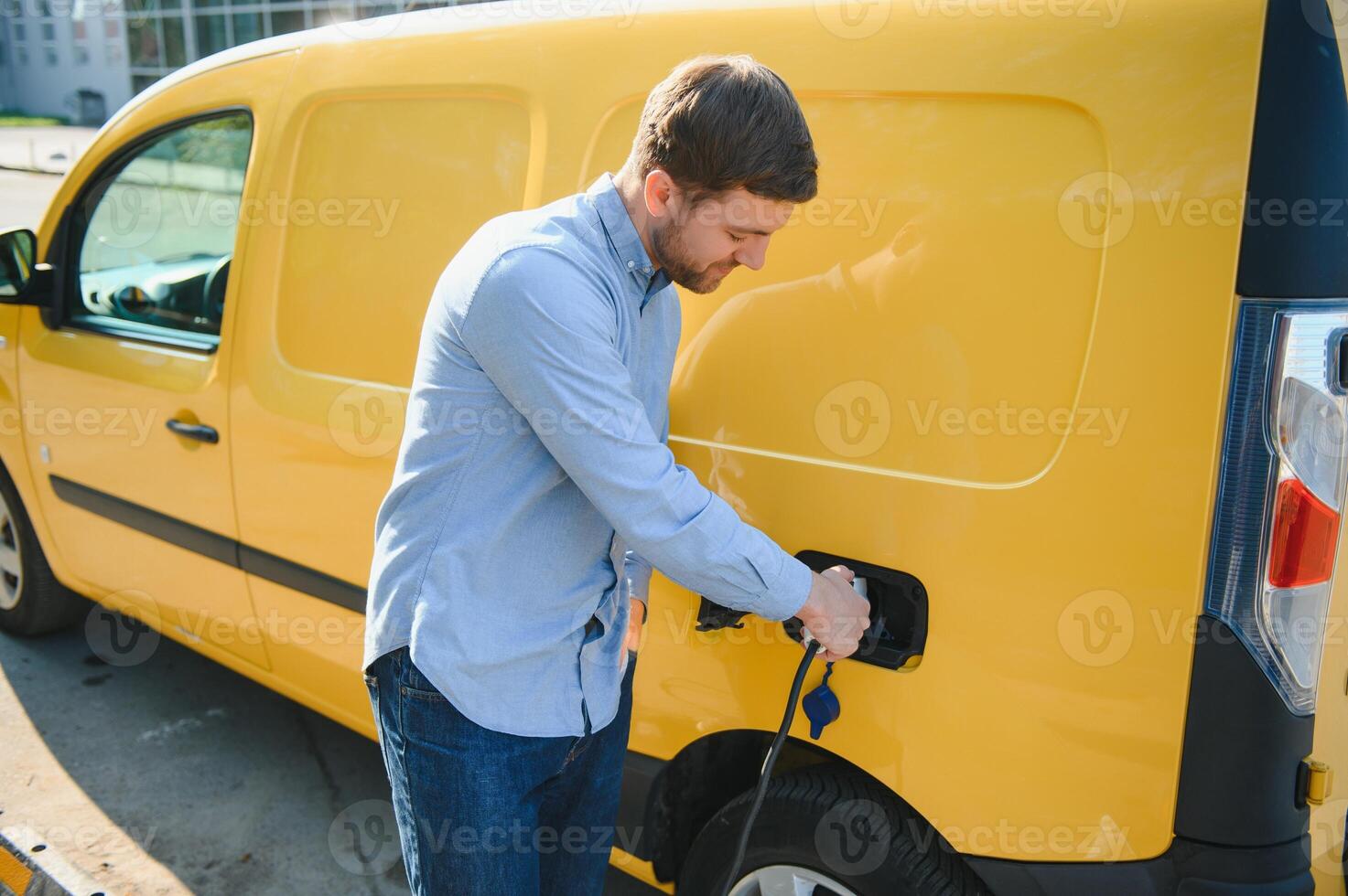 Smiling man unplugging the charger from the car photo