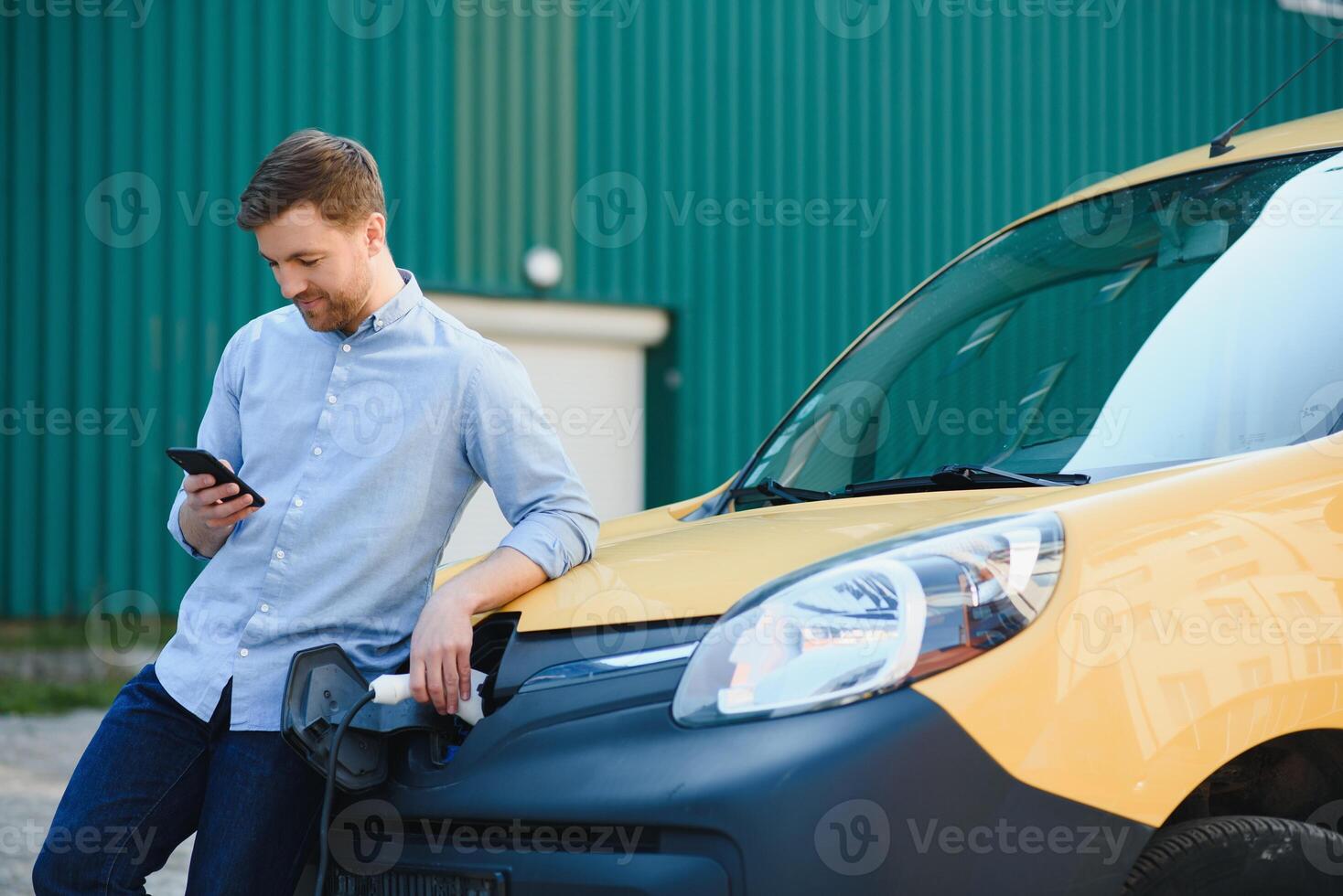Smiling man unplugging the charger from the car photo