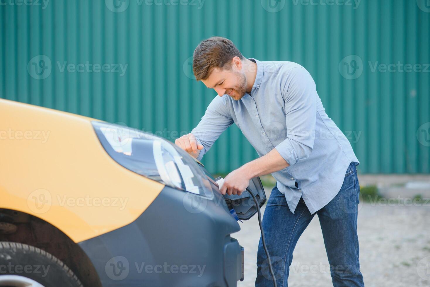Smiling man unplugging the charger from the car photo